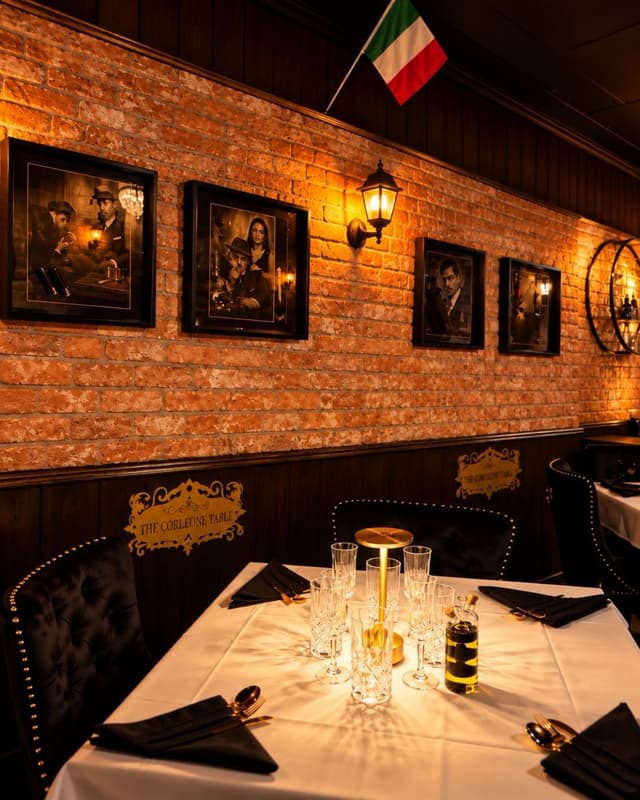 The Corleone Table at The Goodfellas Pizzeria, set beneath framed portraits and an Italian flag.